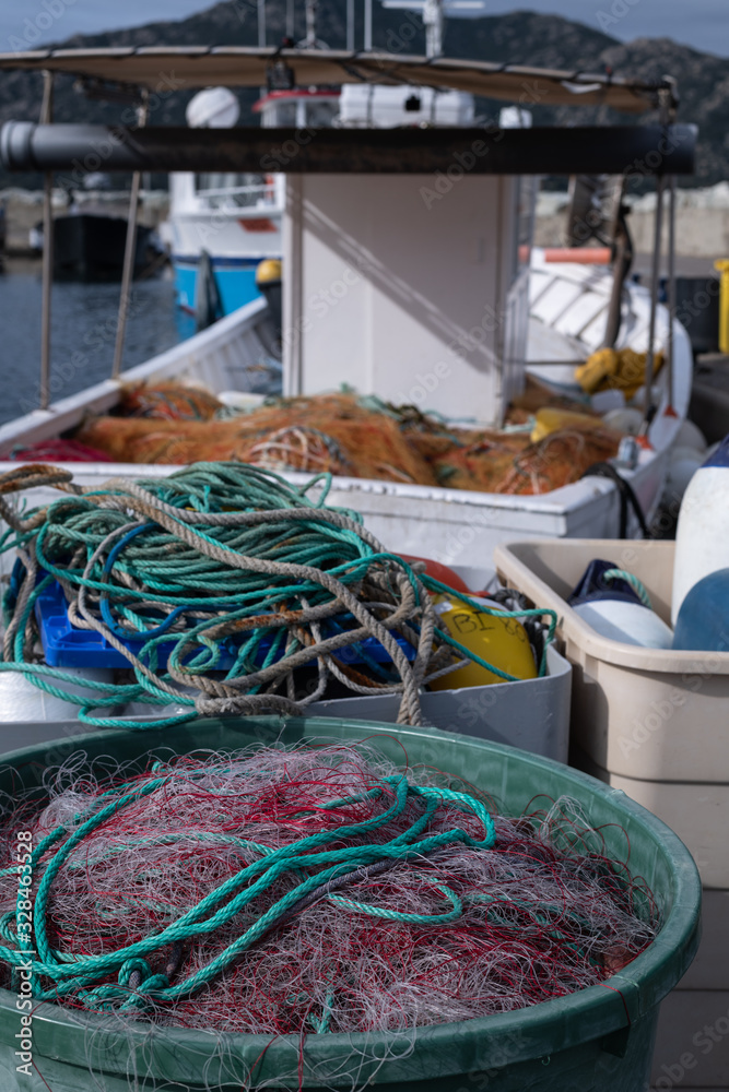 Fishing nets piled up on the pier near the fishermen's boats