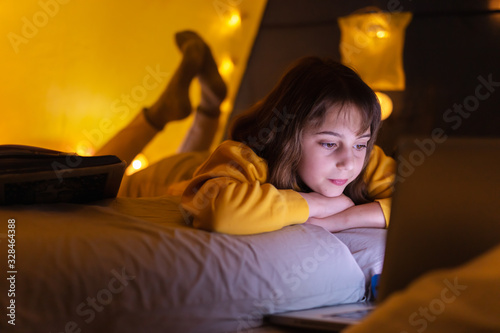 Little 11 year old girl using laptop under her home-made tent inside the living room.