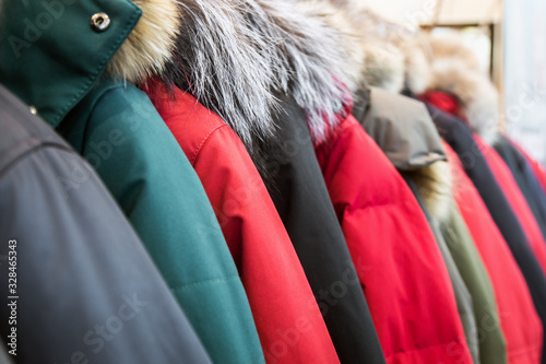 assortment of winter jackets and down jackets on store hangers. photo