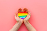 LGBT symbol. Rainbow heart in hands on pink background top-down