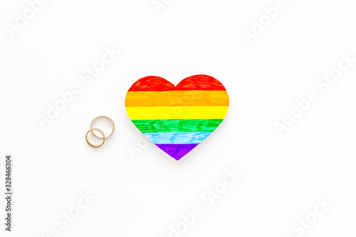 LGBT weddings. Rainbow heart near rings on white background top-down copy space © 9dreamstudio