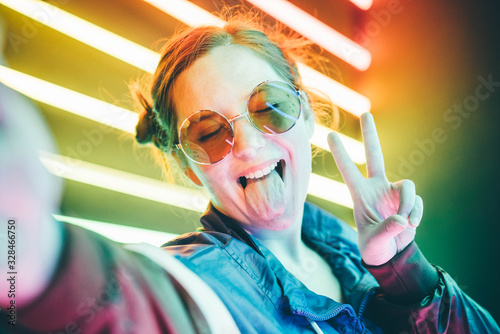 Portrait of modern young woman making selfie at the neon light. photo