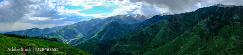 Panoramic landscape of Almaty mountains with cloudy stormy clouds. Overcast - weather storm. Rain in mountains.
