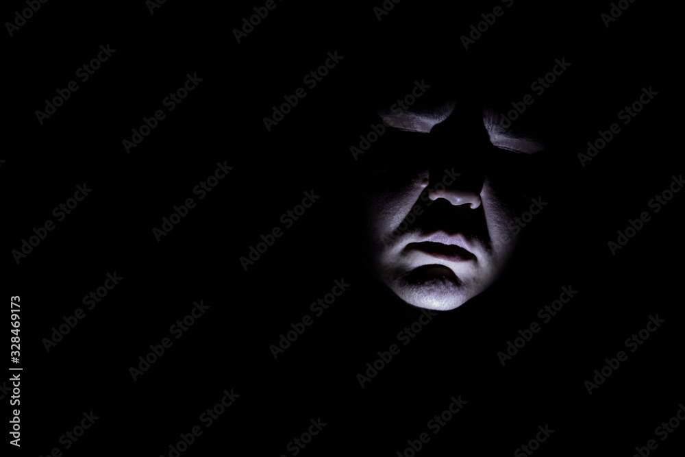Maniac face silhouette illuminated by torch on black background. Dark background. Horror background. Black background. Halloween horror concept.