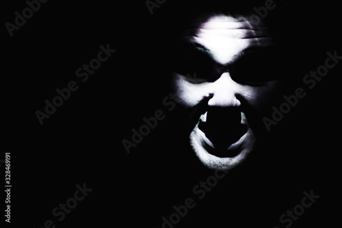 Canvas Print Maniac face silhouette illuminated by torch on black background