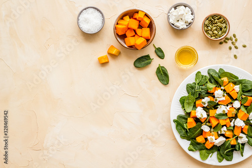 Salad with pumpkin and basil - near ingredients - on beige background top-down copy space © 9dreamstudio