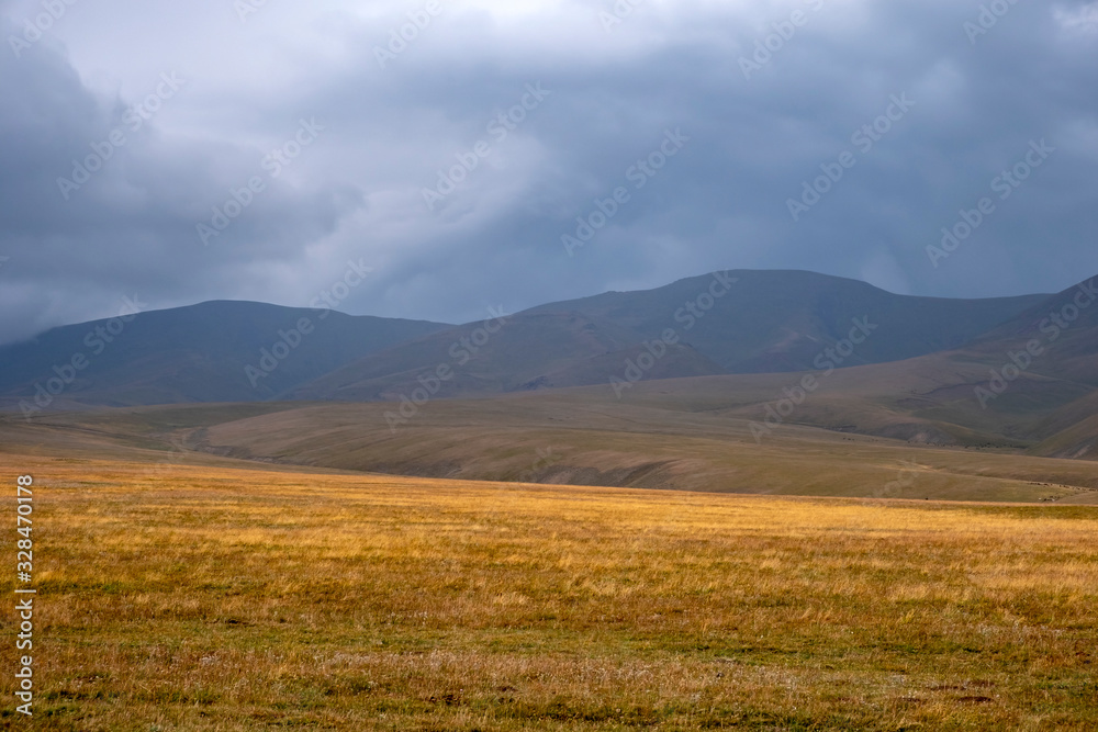 Scenic mountain valley landscape with rain clouds background. Nature background. Rural scenery. Dramatic scene. Autumn background. Mountain valley. Assy plateau in Kazakhstan.