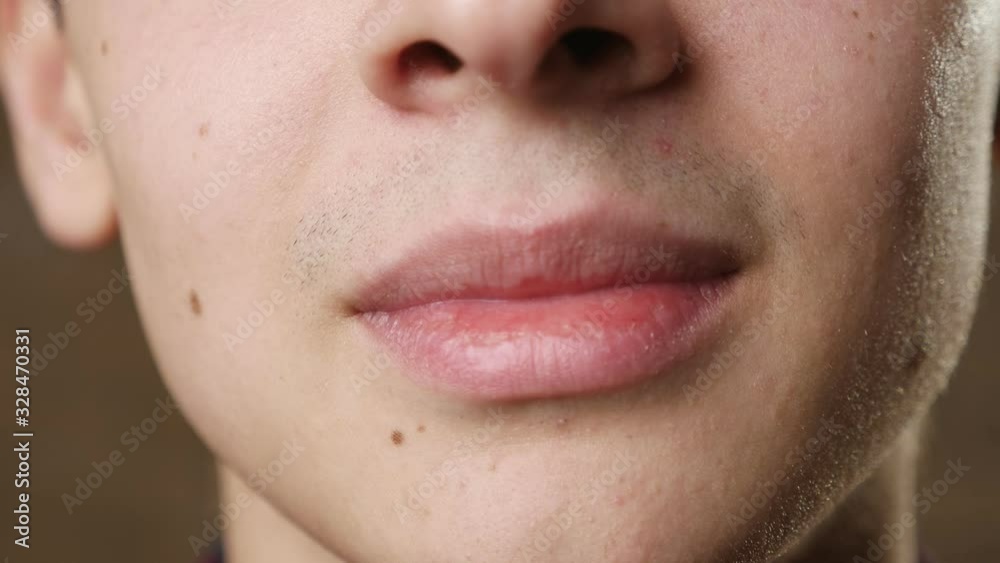Young male lips smiling cheerfully in a brick studio, looking funny and original Young male lips smiling cheerfully in a brick studio, looking funny and original