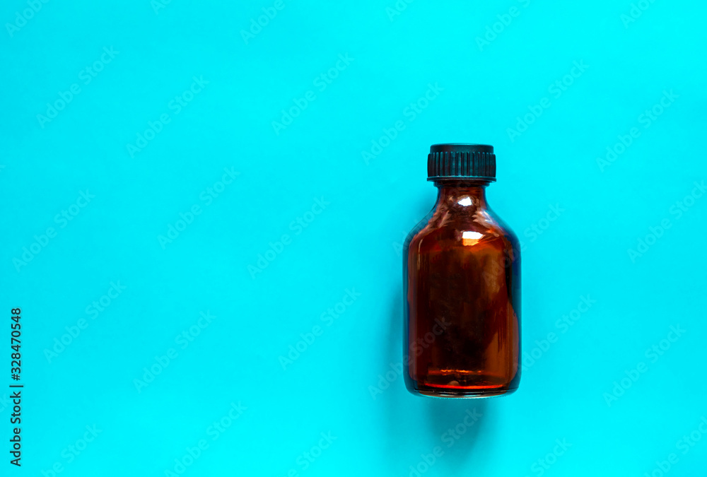 Glass bottle for medicine on blue background. Brown bottle for liquids. Glass bottle for medicine on blue background. Brown bottle for liquids.