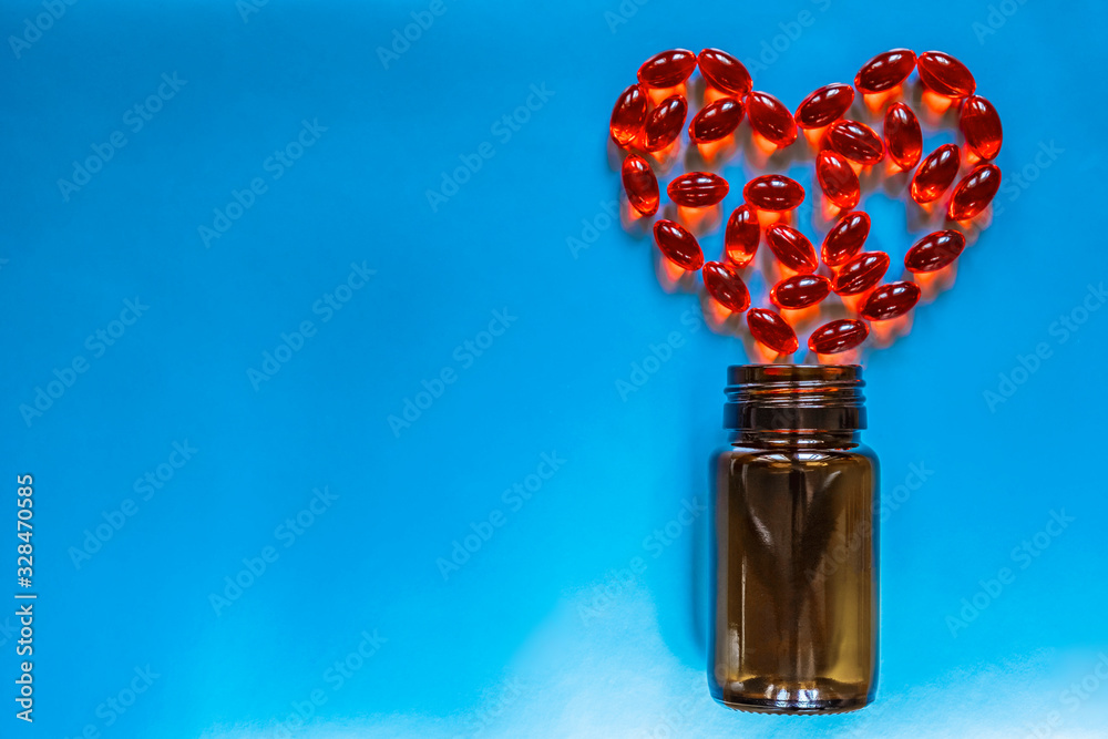 The red pills in heart shape on a blue background. Heart diseases problems concept.
