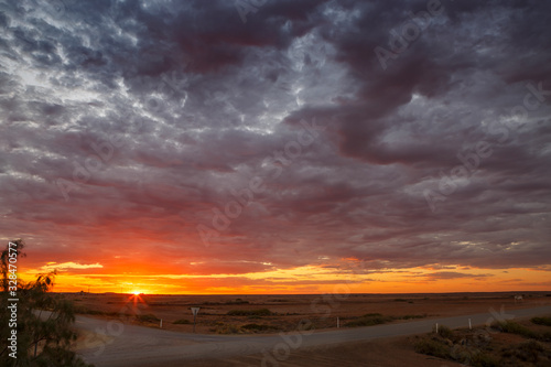Marree crossroads with dramatic clouds, orange and purple summer sunset and copy space, taken in the Australian outback town of Marree,South Australia