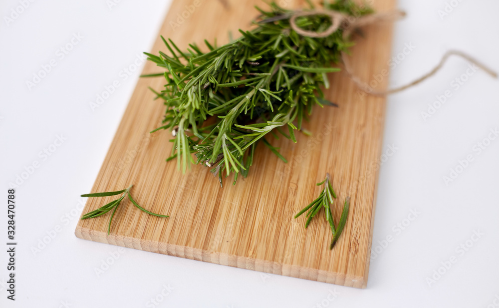 greens, culinary and ethnoscience concept - bunch of rosemary on wooden cutting board greens, culinary and ethnoscience concept - bunch of rosemary on wooden cutting board