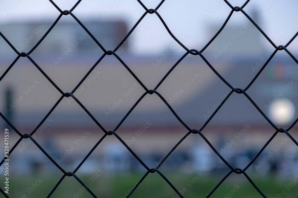 Chain link fence on a blurred city background. Metall wire fence with unfocused city backgorund. Chain link fence on a blurred city background. Metall wire fence with unfocused city backgorund.