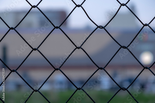 Chain link fence on a blurred city background. Metall wire fence with unfocused city backgorund.