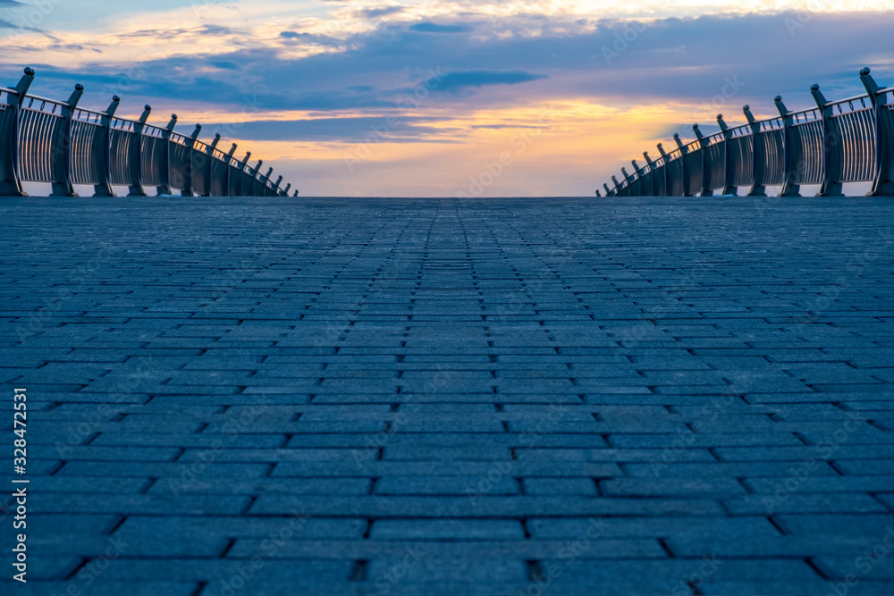 Stone pavement on a pedestrian bridge against beautiful cloudy sky with sunset.
