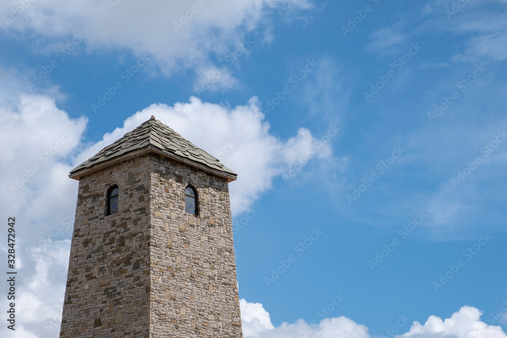 Ancient stone tower on a blue cloudy sky background.