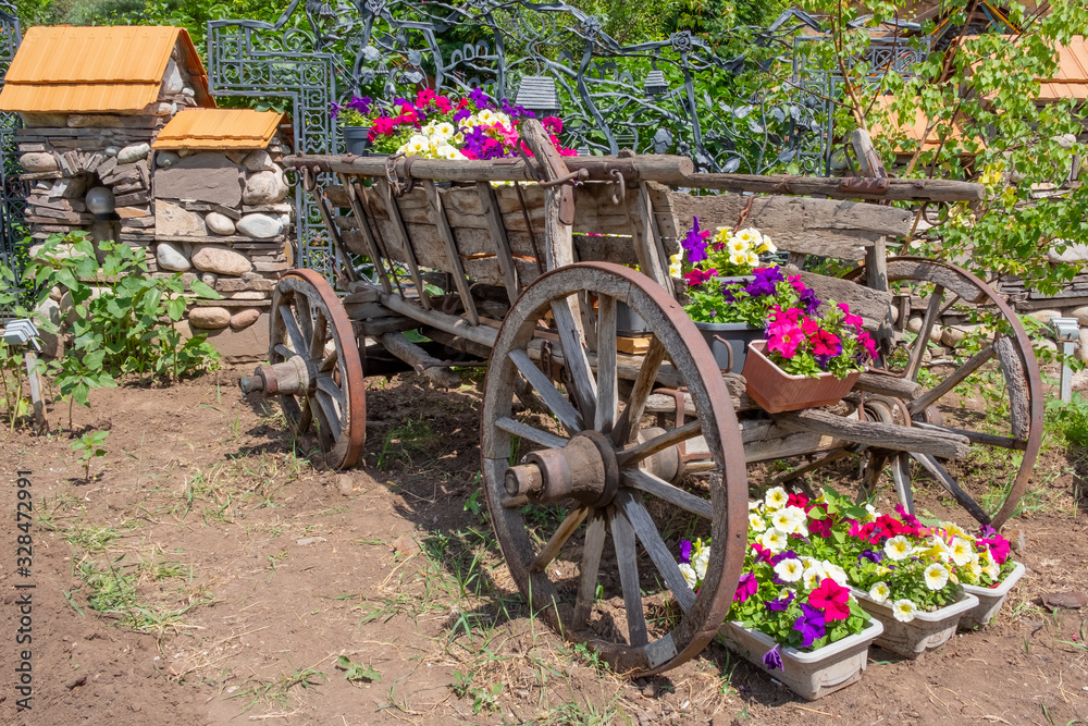 Old wooden wagon decorated with flowers on pots.