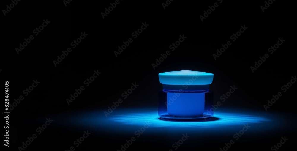 a jar of daily moisturizer for the face in a beam of blue light on a dark black background a jar of daily moisturizer for the face in a beam of blue light on a dark black background
