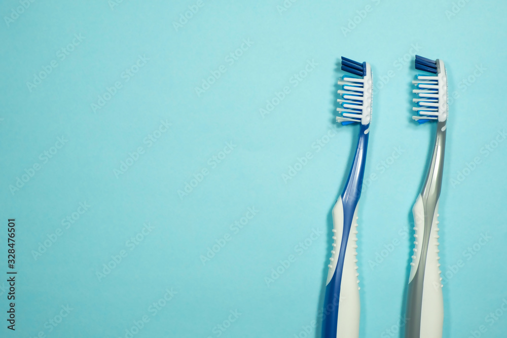 Closeup of two new plastic toothbrushes on a blue background. Dental heathcare concept. Closeup of two new plastic toothbrushes on a blue background. Dental heathcare concept.