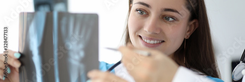 Portrait of wonderful nurse looking at x-ray of body parts with happiness and smile. Lovely woman in medical uniform with stethoscope. Medical and healthcare concept