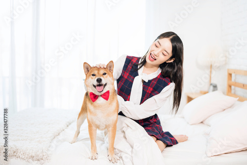 Pet Lover concept. An Asian woman is resting with a Shiba Inu dog on bed in bed room. Shiba Inu is a Japanese dog that is famous throughout the world. Selective focus. © Thirawatana