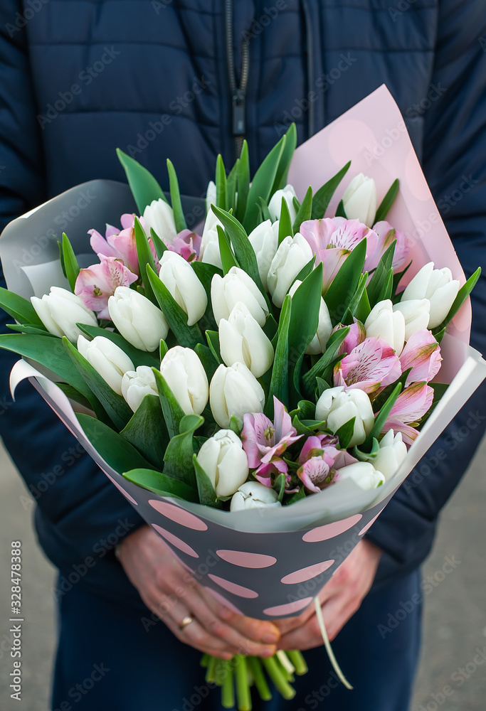 The woman holding a bouquet of white tulips. Girl child holding a bouquet of spring tulips in front.