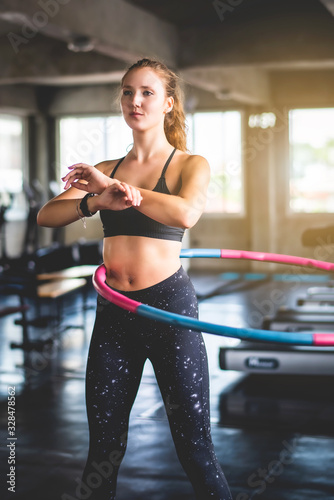 Beautiful young caucasian woman doing hula hoop during an exercise class at sport gym. Healthy sports lifestyle, Fitness, Healthy and workout concept.