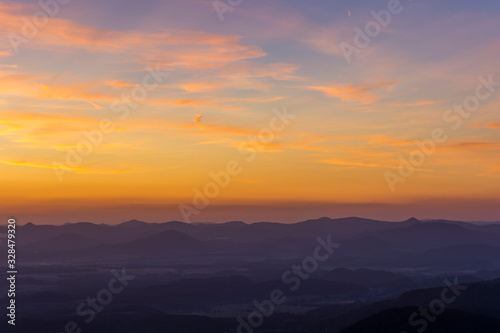 Clearly bright sunset. Orange clouds above sunset. Silhouette of rocks in the front. © Petr