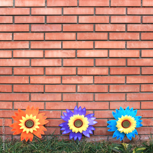 Bright plastic flowers on a brick wall background. Space for text