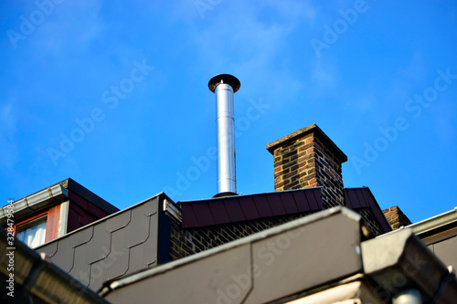 Closeup of roof with chimney over blue sky background.