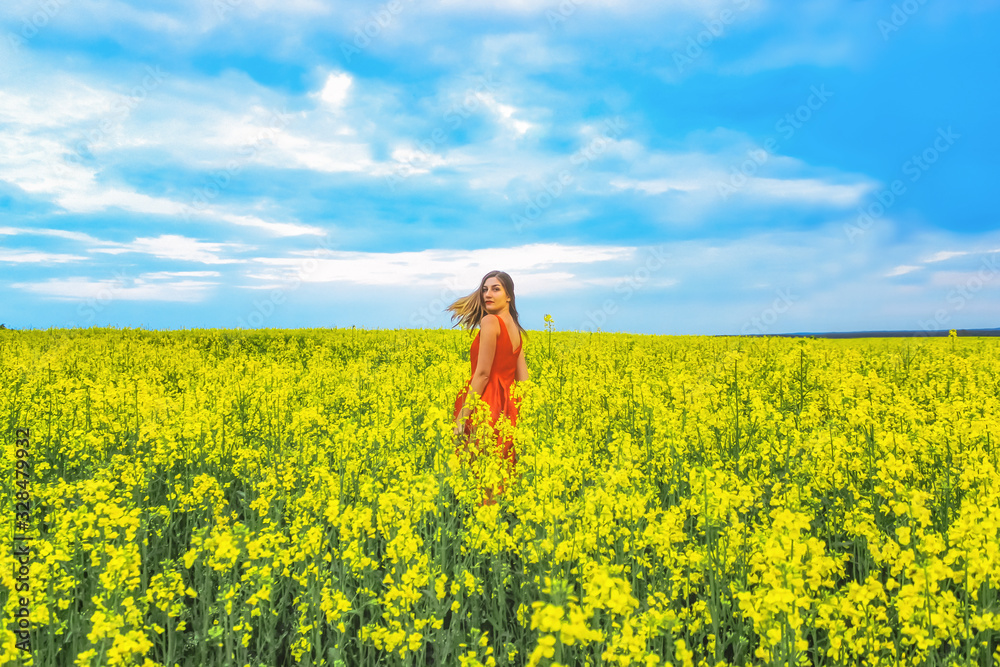 Young beautiful girl in a red dress close up in the middle of yellow field with radish flowers at sunset time. Young beautiful girl in a red dress close up in the middle of yellow field with radish flowers at sunset time.
