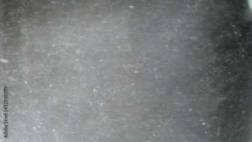 White particles swirling in a glass of water