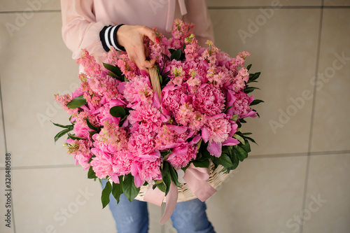 Large bouquet of pink flowers in a basket in girl's hands
