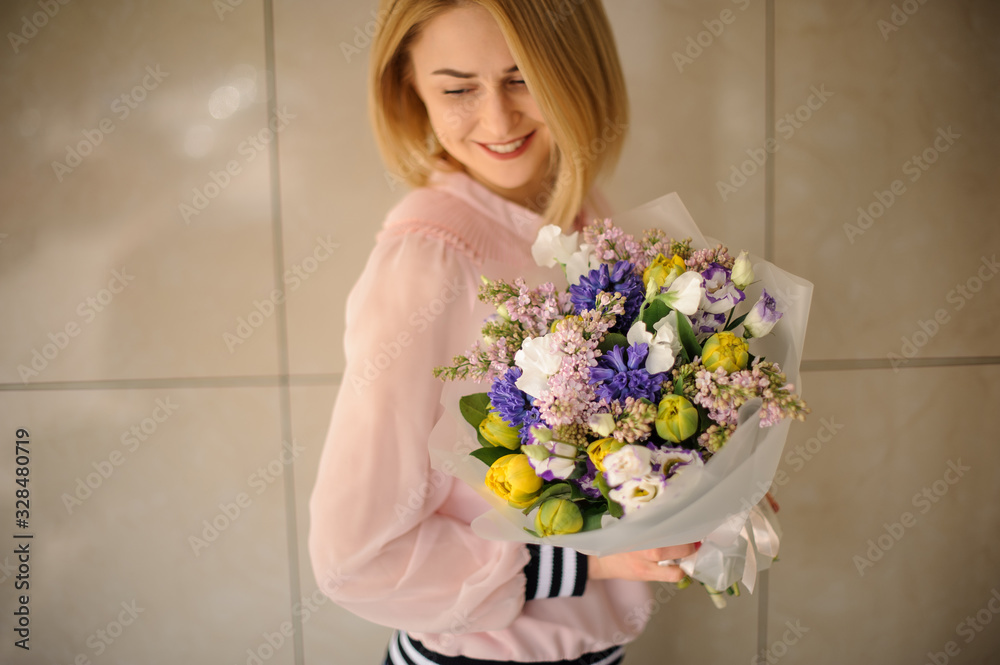 Smiling woman holding a beautiful flower bouquet of different fresh flowers.