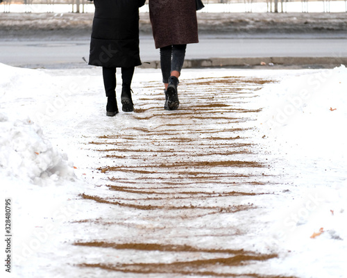 The pavement is sprinkled with sand. People walk on it