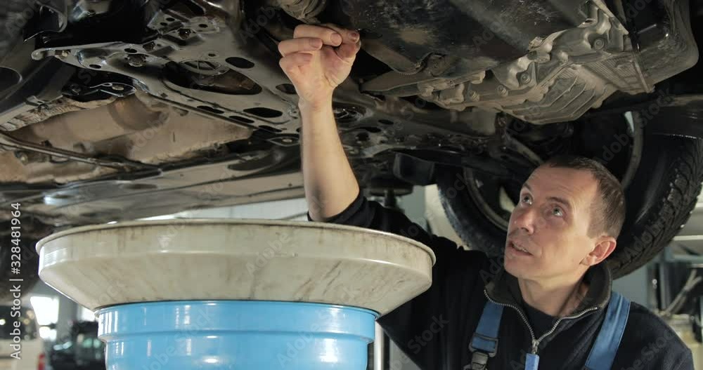 Mechanic Drains Old Used Engine Oil From A Car