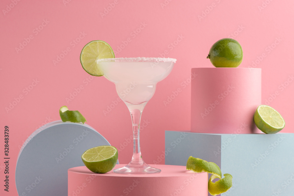 Glass of Margarita cocktail and fresh limes on pink background - obrazy, fototapety, plakaty 