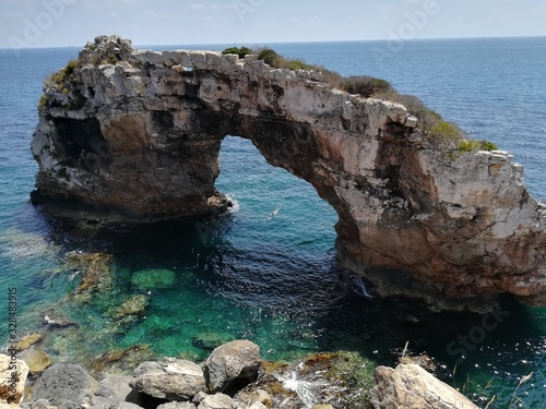 Rock arch isolated in the sea next to the coast. © Sofia ZA