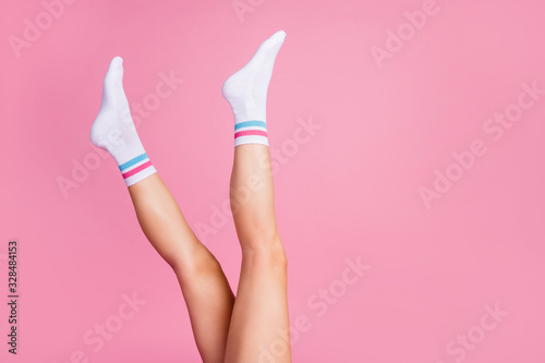 Cropped profile side view of nice attractive vertical long feminine legs wearing white casual soft socks perfect skin care skincare bodycare isolated over pink pastel color background