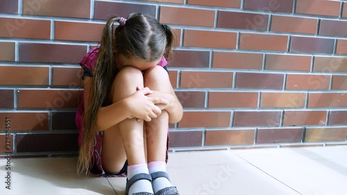 Child abuse. Little girl crying, sitting on the floor photo