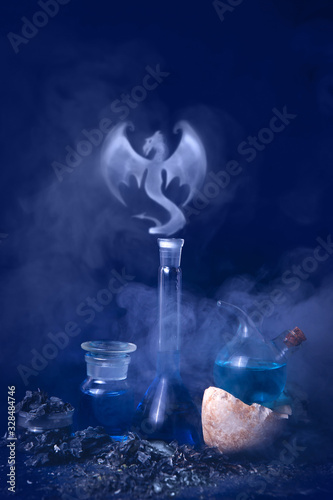 Laboratory glassware on a blue background. A dragon born from smoke. Magical experiences. Background of blue classic color.
