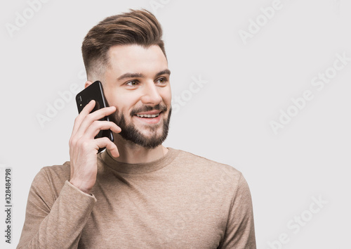 Young handsome smiling man talking on mobile phone isolated closeup studio portrait