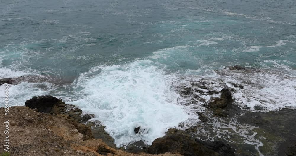 Water crashing of the ocean to the rocky shores of the island and reflecting off the rocks it meets on its way to the shore 4k slow motion capture at 60fps Water crashing of the ocean to the rocky shores of the island and reflecting off the rocks it meets on its way to the shore 4k slow motion capture at 60fps