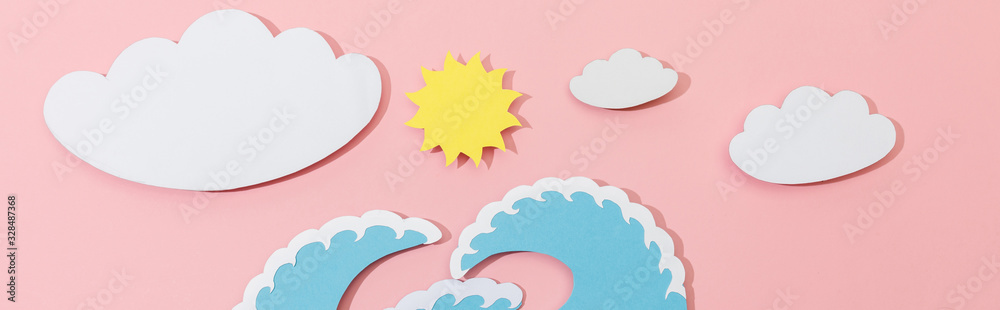 Top view of paper cut sea waves, clouds and sun on pink background, panoramic shot