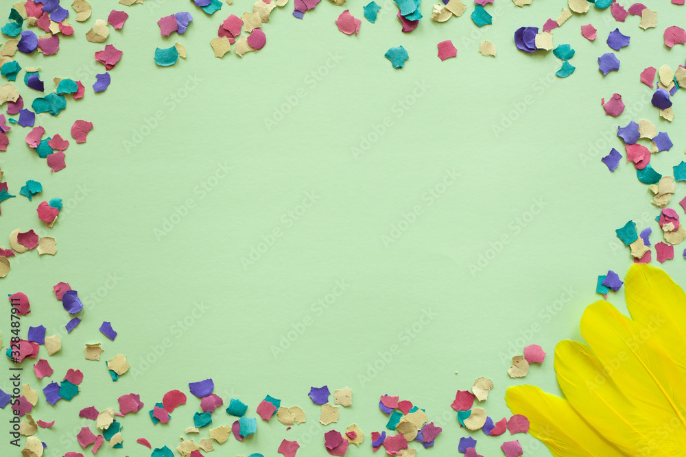 Purim carnival green background with colorful confetti and yellow feathers