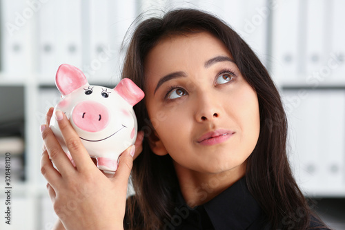 young beautiful chinese brunette woman hold piggybank in arms photo