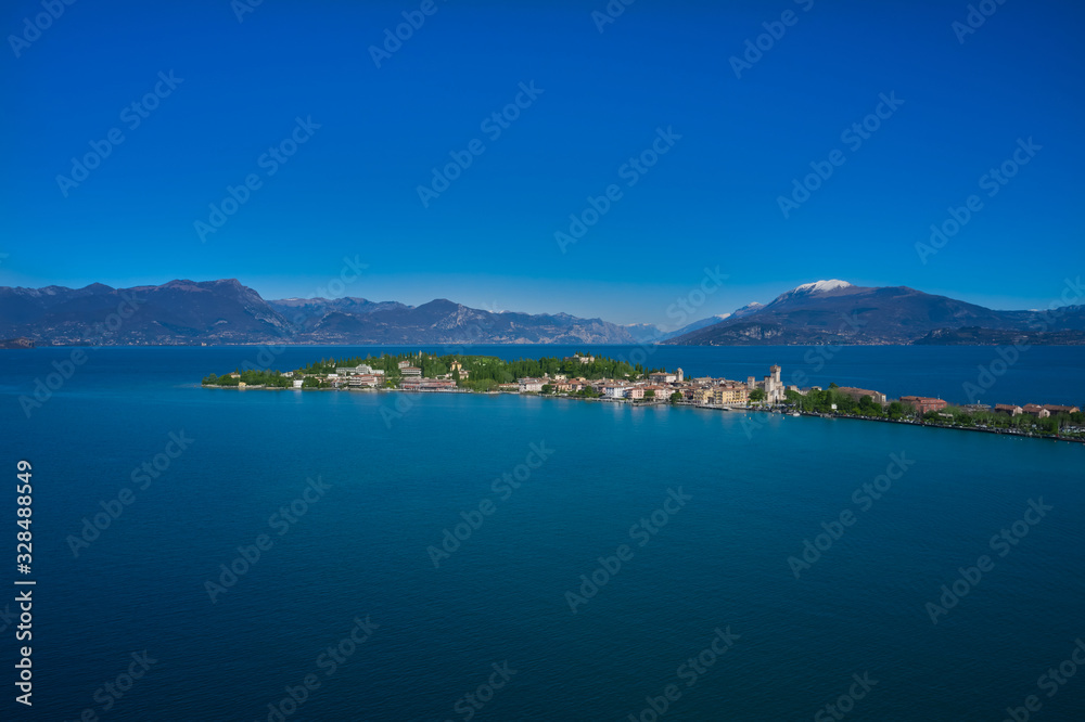 Sirmione island Lake Garda, Italy. Aerial view. In the background mountains in the snow and blue sky