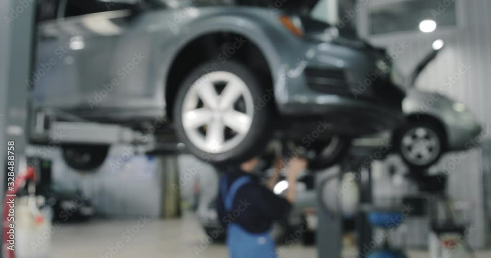 Blurred Background. Auto Mechanic Working On Car. Dealer Service Center Blurred Background. Auto Mechanic Working On Car. Dealer Service Center