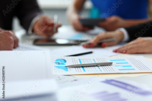 Silver pen lie on important paper at table with group of colleagues in background closeup. Paperwork job trade balance bank credit loan money invest payment irs commerce partnership concept