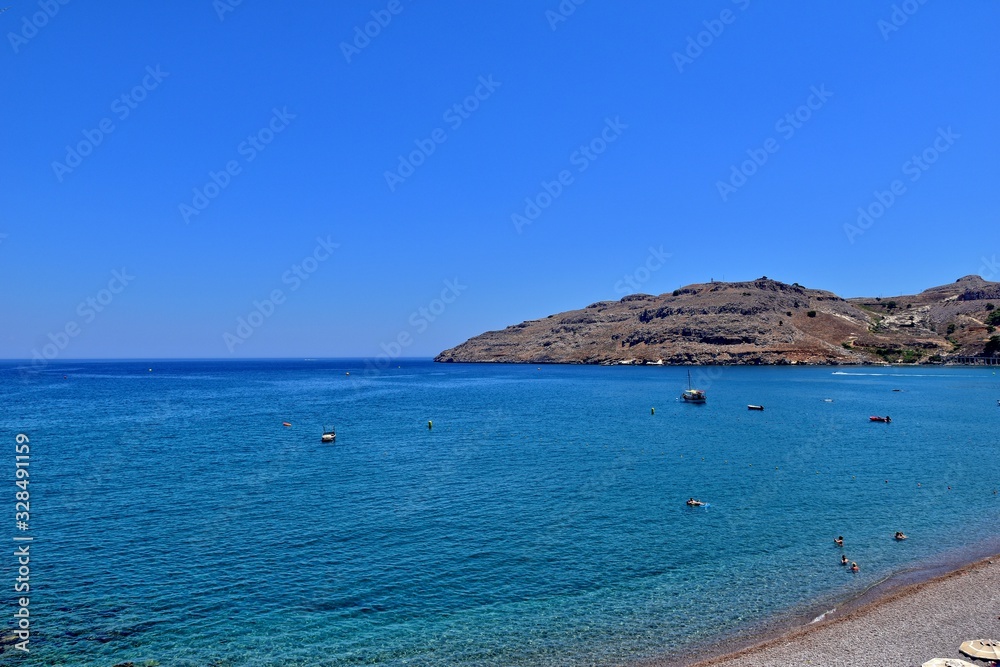  beach on the Greek island of Rhodes with blue water and a strip on a hot summer's vacation day